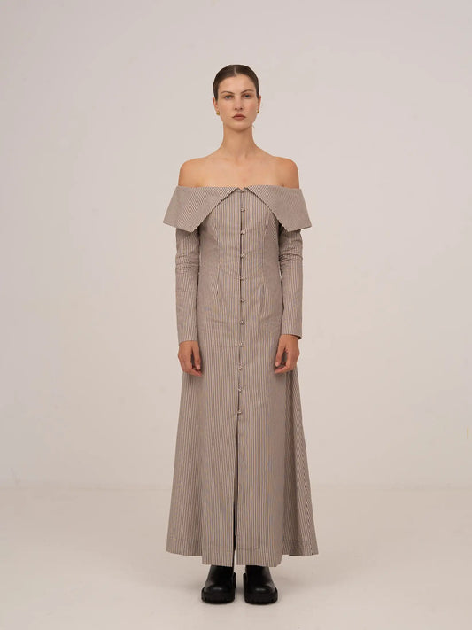 Vestido largo de rayas en tonos marrón y beige, con escote bardot off-shoulder, manga larga ajustada y silueta recta de caída fluida.