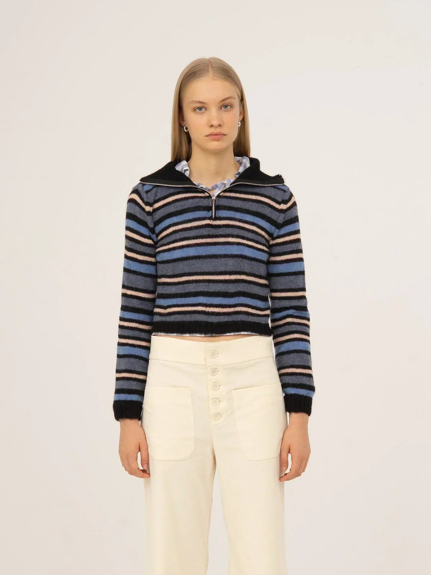 Top de punto a rayas en tonos azul y negro, con cuello tipo polo, manga larga y silueta ajustada, presentado sobre modelo en estudio con fondo neutro.