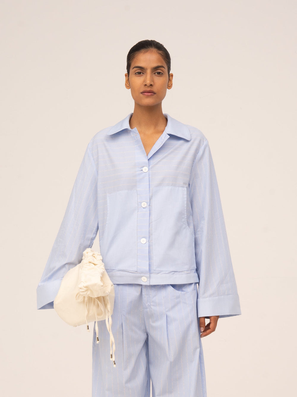 Camisa azul claro de manga larga con botones frontales, corte relajado y tejido ligero con textura sutil.