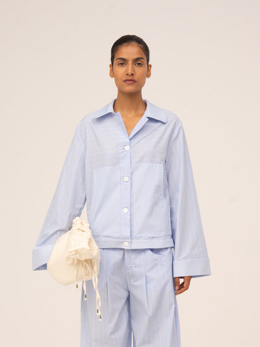 Camisa azul claro de manga larga con botones frontales, corte relajado y tejido ligero con textura sutil.