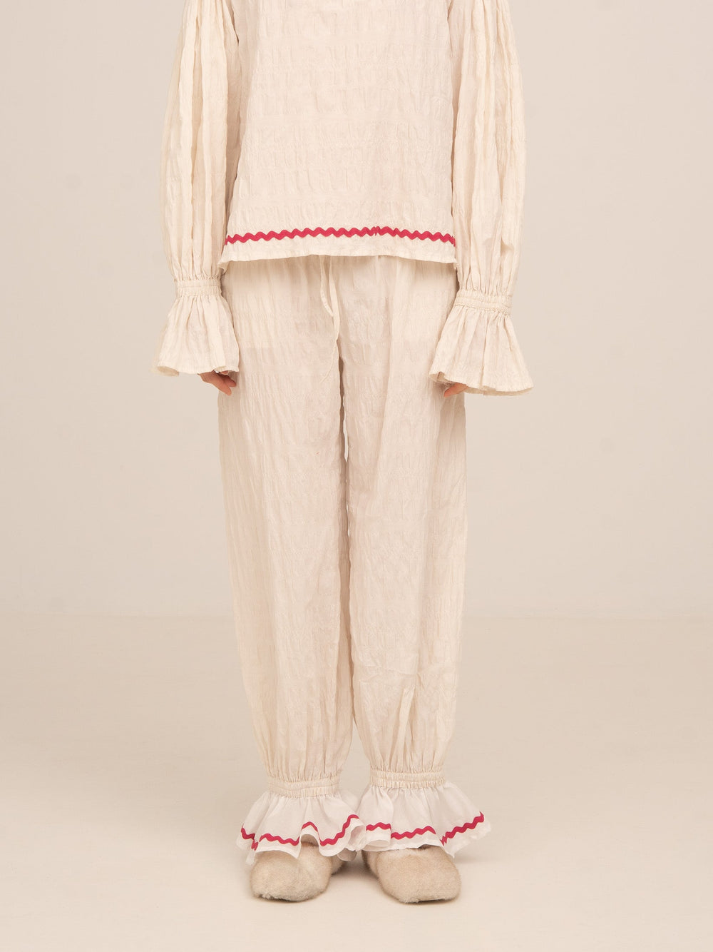 Pantalón de pijama color crema de Carmen Says con bajo elástico y detalle de volante en contraste rojo, diseño cómodo y femenino ideal para looks de descanso con estilo.