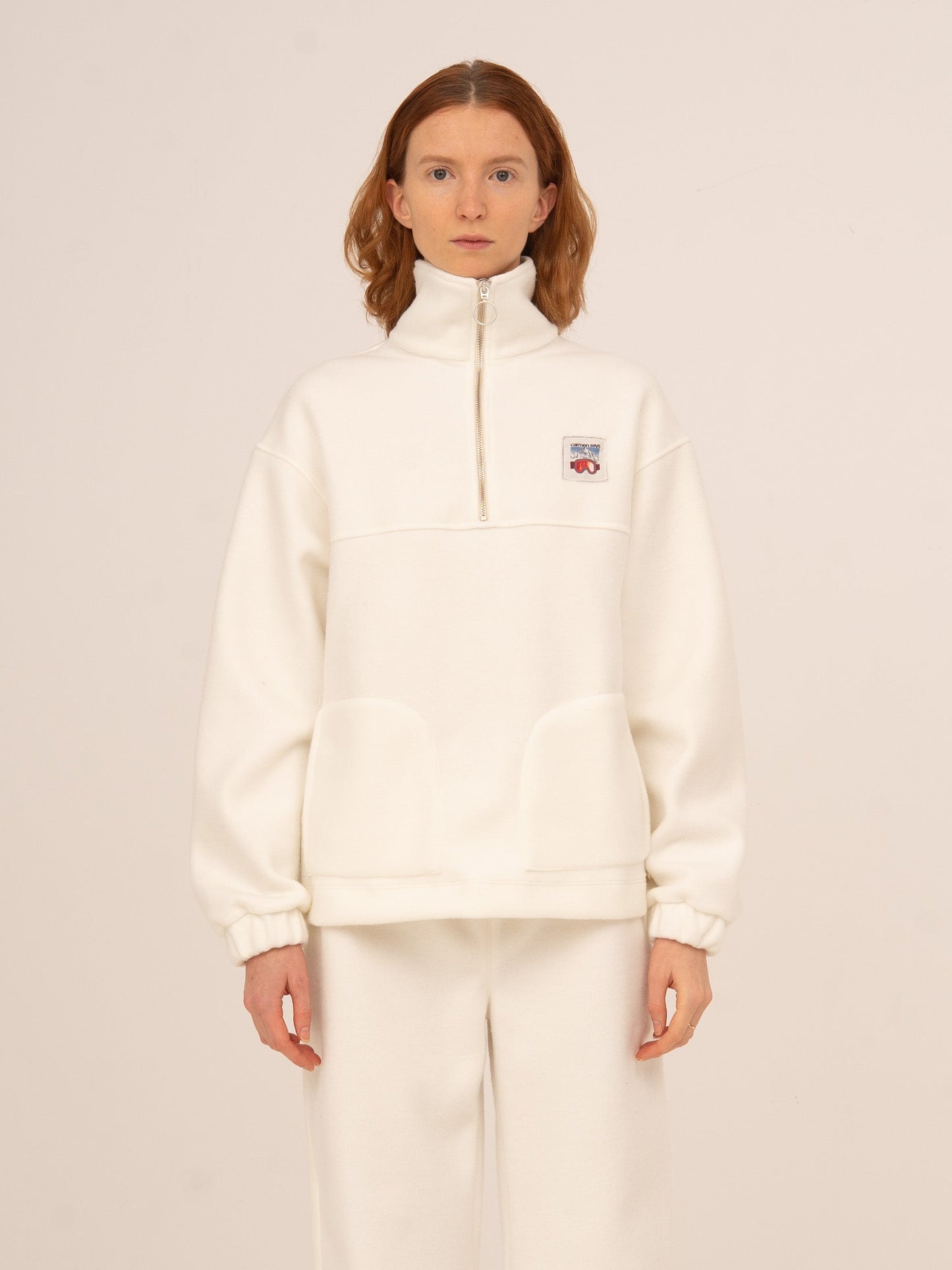 Sudadera femenina en color blanco con cuello alto y media cremallera, tejido suave tipo polar y corte relajado, ideal para looks cómodos y elegantes de invierno, après-ski o estilo casual urbano.