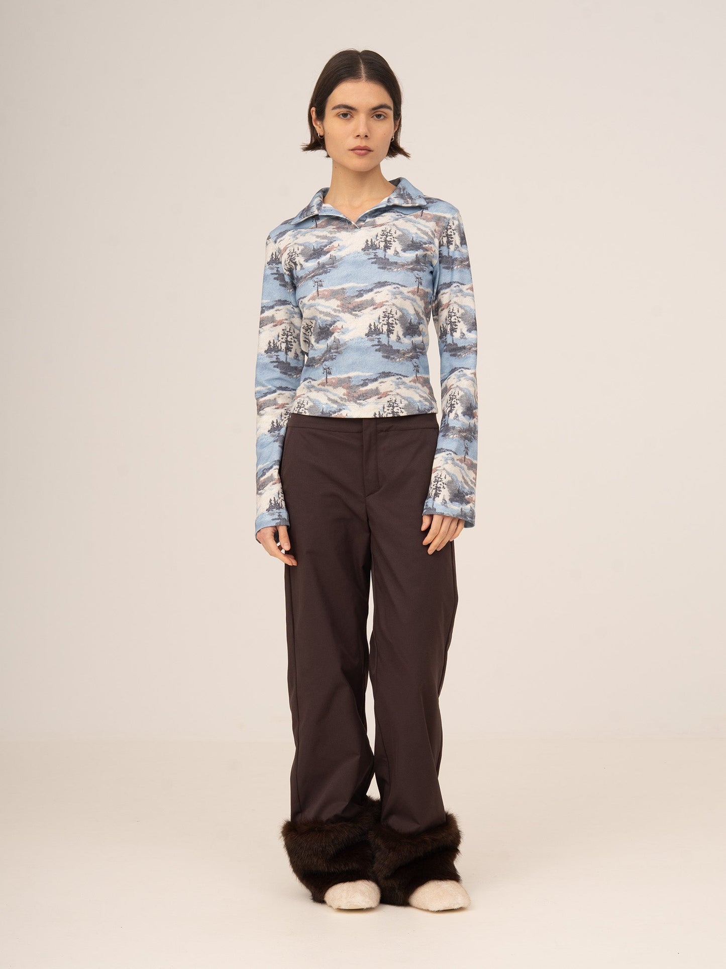 Top femenino de manga larga en tonos azules con estampado artístico inspirado en paisajes de ski, cuello tipo polo y corte ajustado, elegante y moderno para looks sofisticados de día o estilismos de invierno con personalidad.