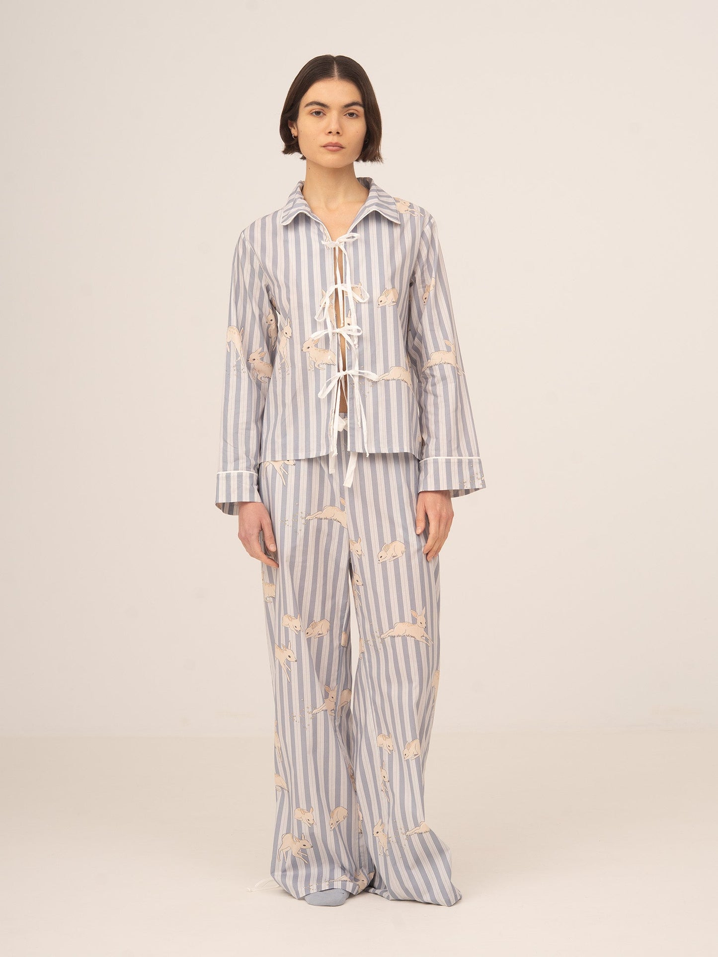 Conjunto de pijama femenino de dos piezas en azul con rayas y estampado floral, compuesto por camisa de manga larga con lazos frontales y pantalón largo fluido, elegante y cómodo para estar en casa con estilo.