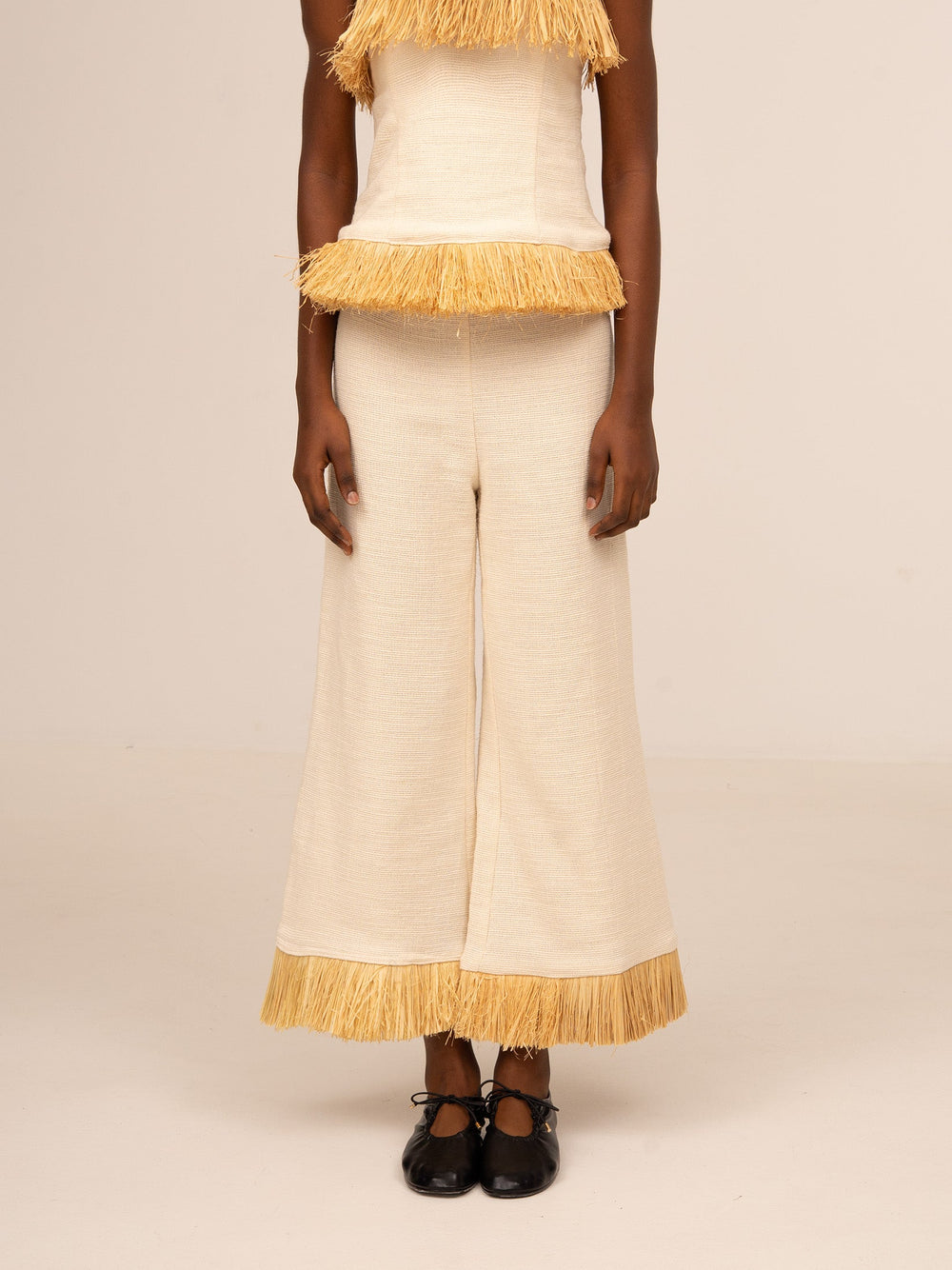 Pantalón ancho color crudo para mujer con detalle de flecos en el bajo