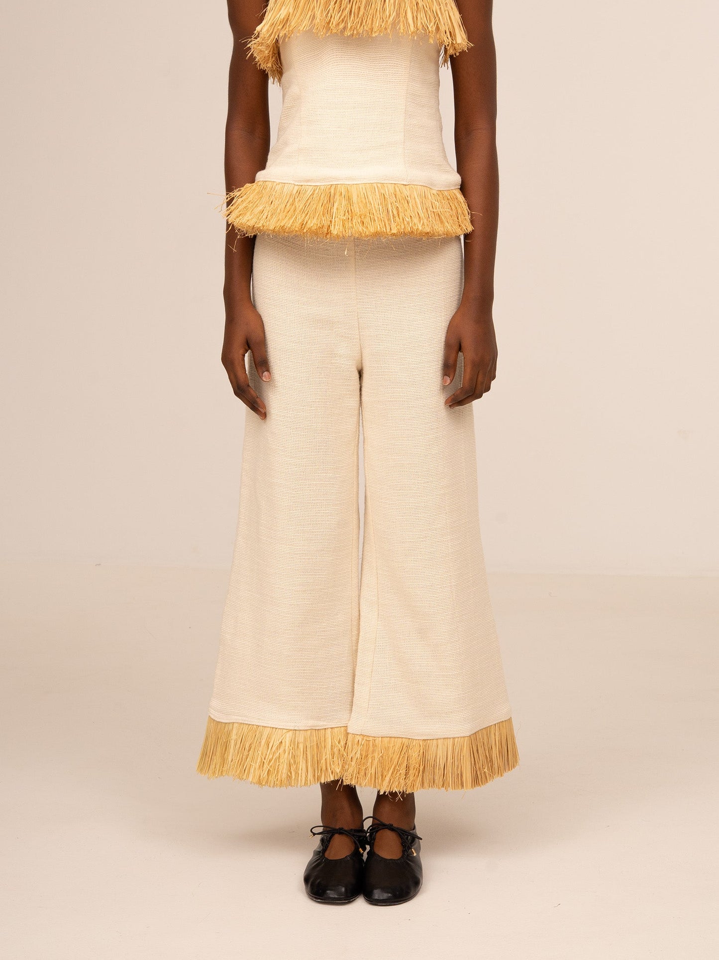 Pantalón ancho color crudo para mujer con detalle de flecos en el bajo