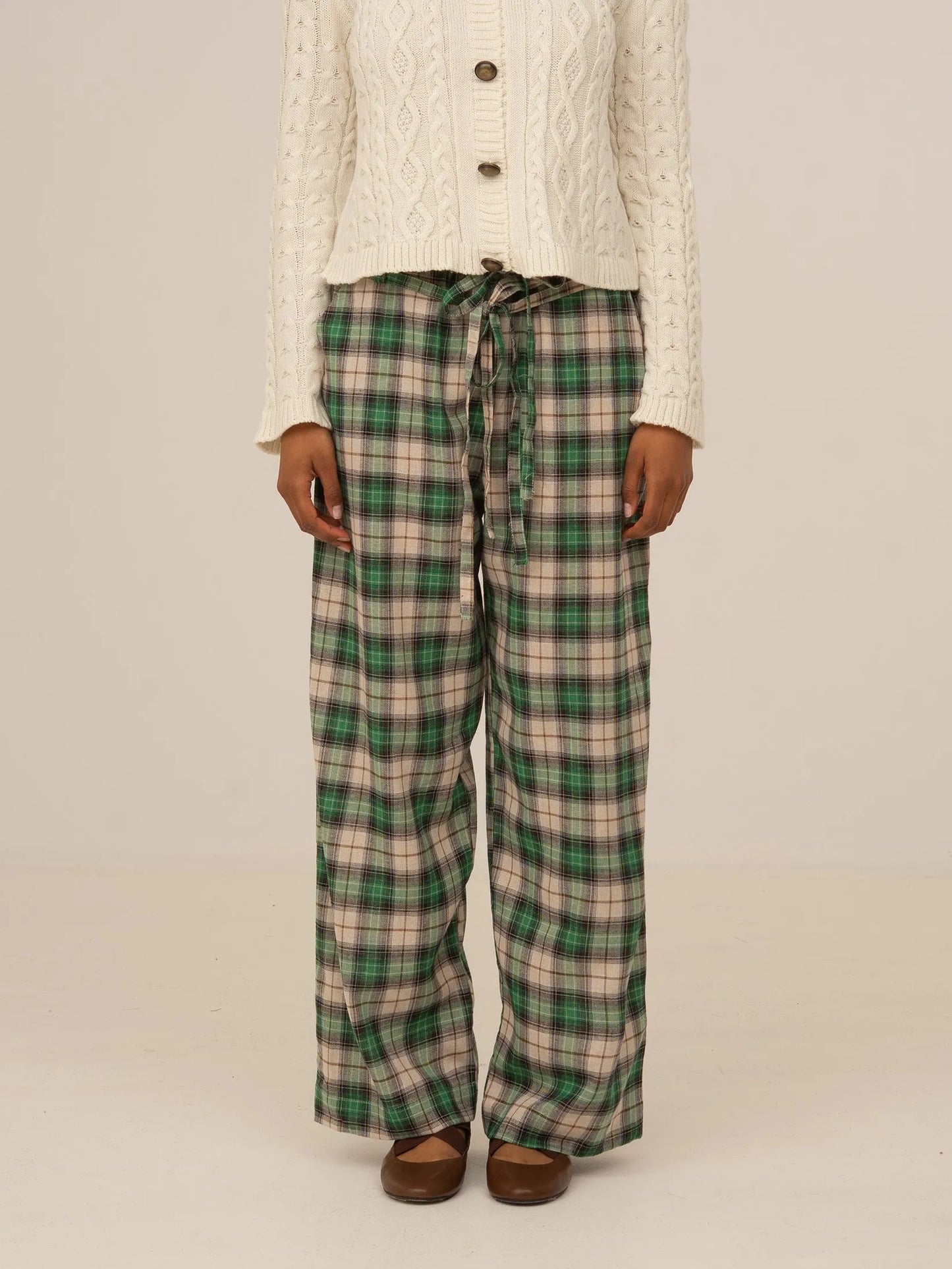 Pantalón largo de cuadros verdes tipo tartán, corte recto y cintura con cordón ajustable, presentado sobre modelo en estudio con fondo neutro.