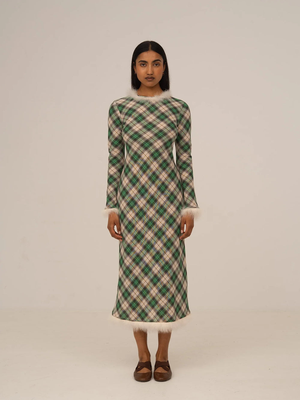 Vestido midi verde de cuadros con manga larga y silueta recta, presentado sobre modelo en estudio con fondo neutro.