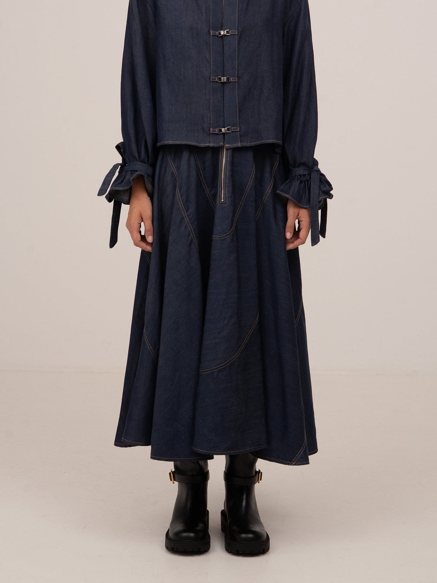 Falda midi de denim azul oscuro con paneles amplios, costuras visibles y silueta fluida de largo medio.