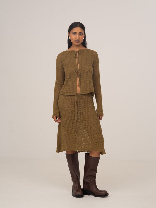 Modelo con falda midi de punto verde CARMEN SAYS, combinada con cárdigan de punto y botas marrones
