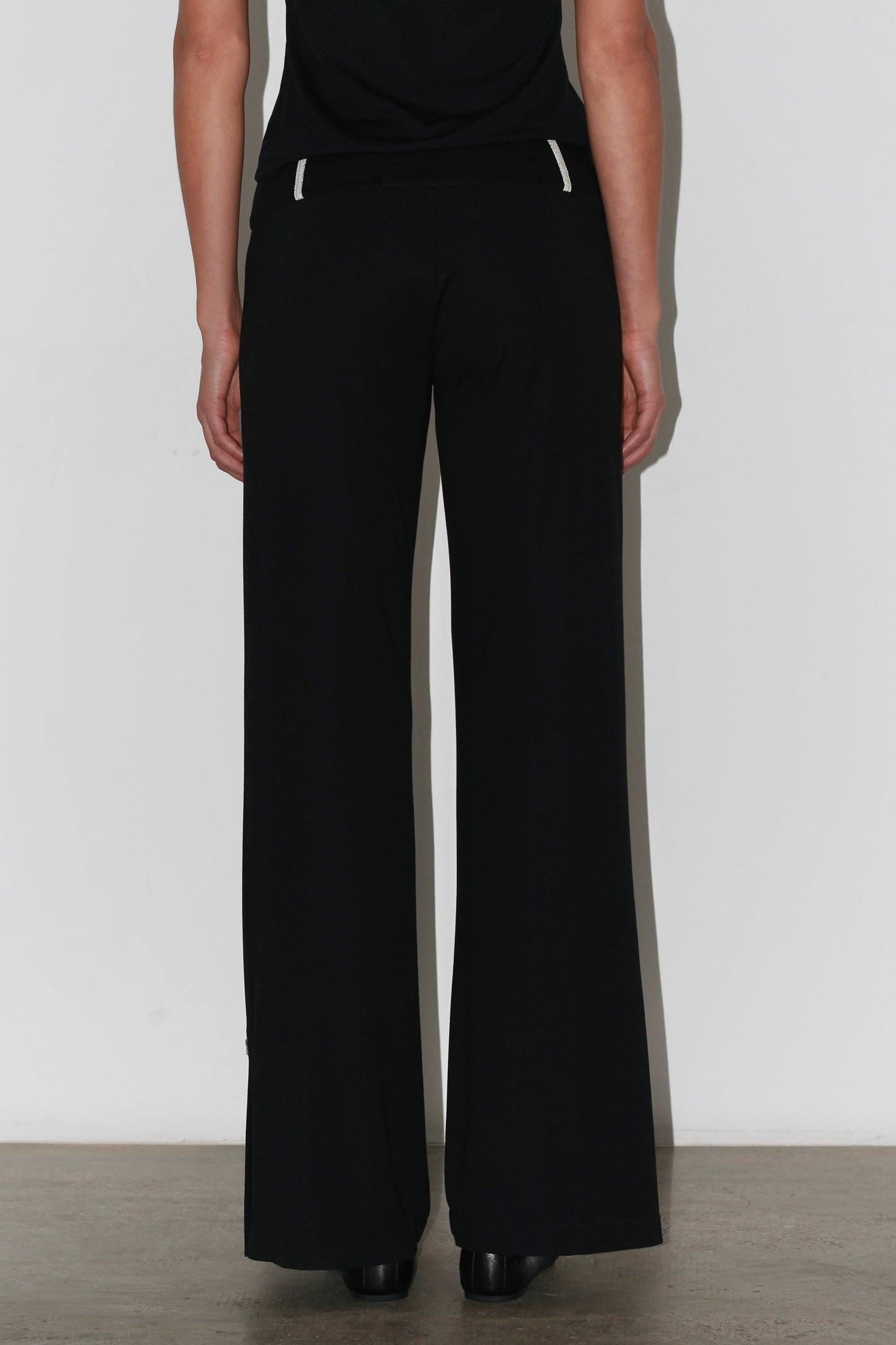 Side view of the Zeynep Pants – tailored black trousers with button details at the ankle.