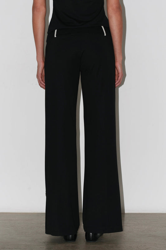 Side view of the Zeynep Pants – tailored black trousers with button details at the ankle.