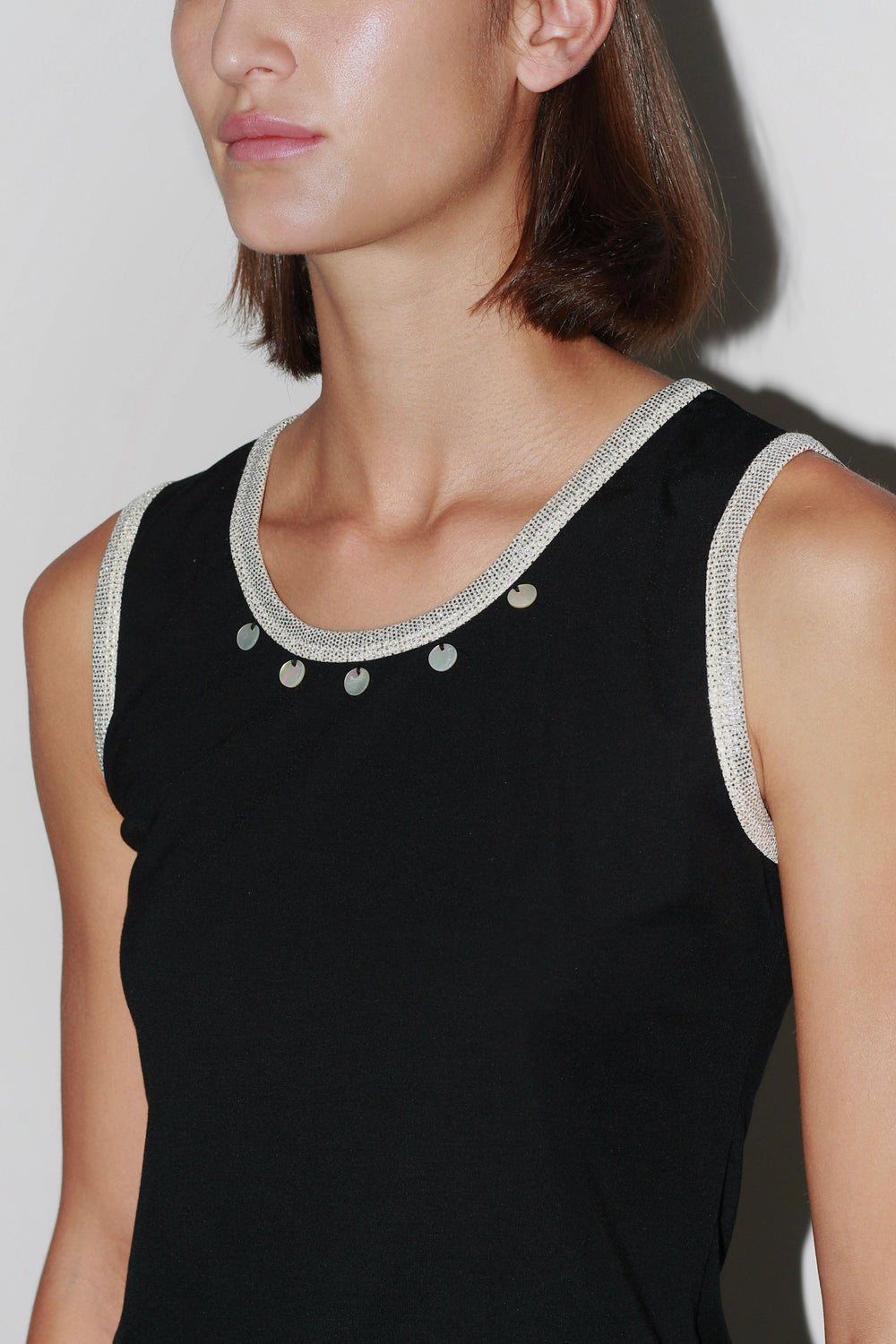 Close-up of the Jade Top – black sleeveless top with pearl-embellished neckline and elegant cut.
