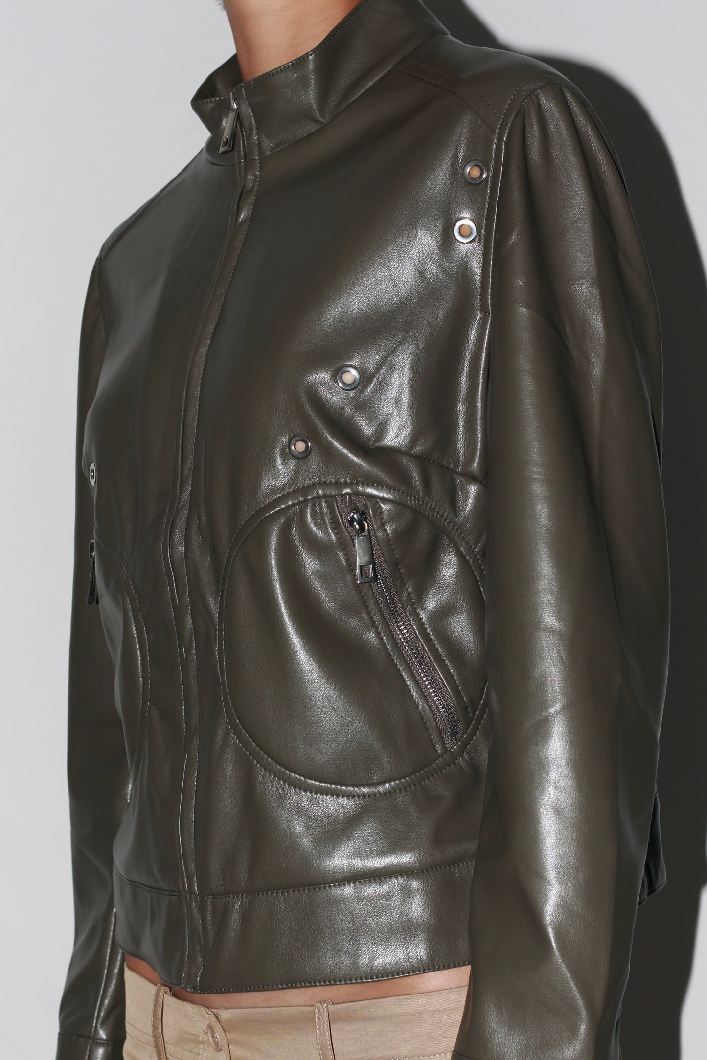 Side close-up – dark green leather jacket showcasing detailed stitching and glossy finish.