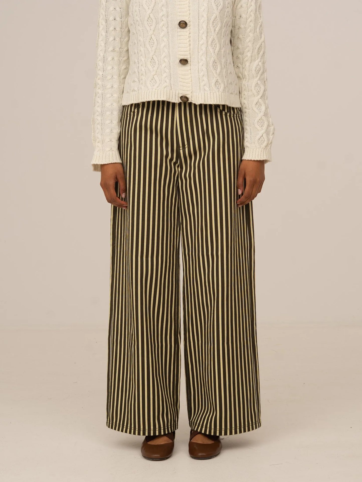 Pantalón vaquero de rayas verticales en verde y beige, de corte recto y tiro medio, presentado sobre modelo en estudio con fondo neutro.