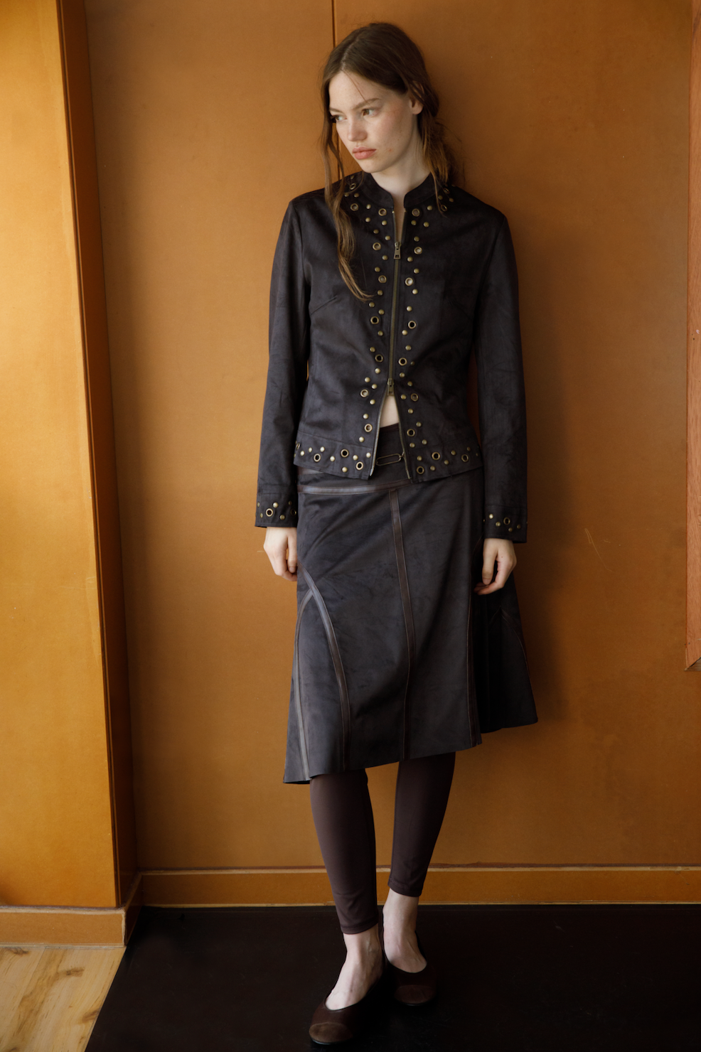 Lifestyle shot – woman wearing the Bella Brown Jacket in a warm indoor setting, timeless and confident Coloma’s style.